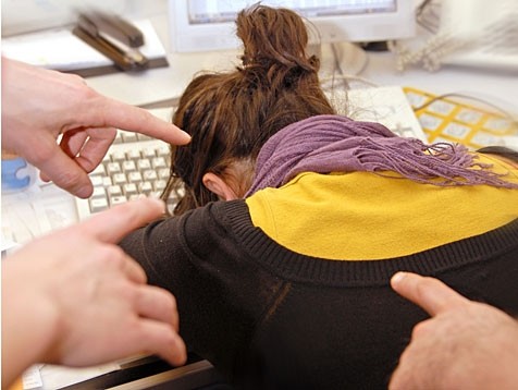 ragazza con il volto rivolto sulla tastiera e delle mani che le puntano il dito